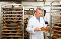 Baker arranging trays with bakery products on trolley Royalty Free Stock Photo