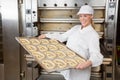 Baker in bakery with baking plate full of pretzels Royalty Free Stock Photo