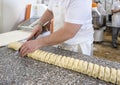 Baker in the bakery cuts rolls rolled out of dough with stuffing for baking buns