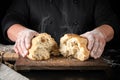 baker in black uniform broke in half a whole baked loaf of white wheat flour bread Royalty Free Stock Photo