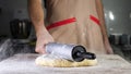 Baker chef is rolling the dough with rolling pin on the table. Royalty Free Stock Photo