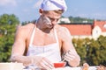 Baker concept. Cook or chef with sexy muscular shoulders and chest covered with flour. Man on busy face wears cooking Royalty Free Stock Photo