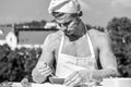 Baker concept. Cook or chef with muscular shoulders and chest covered with flour. Man on busy face wears cooking Royalty Free Stock Photo