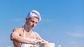 Baker concept. Man on busy face wears cooking hat and apron, sky on background. Cook or chef with sexy muscular Royalty Free Stock Photo