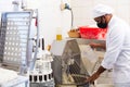 Baker controlling dough making in kneading machine in bakery Royalty Free Stock Photo