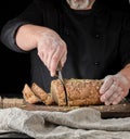 baker cuts a knife into slices of rye bread with pumpkin seeds Royalty Free Stock Photo