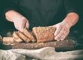 baker cuts a knife into slices of rye bread with pumpkin seeds Royalty Free Stock Photo