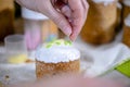 Baker decorates Easter cakes with glazed top with colored sugar sprinkles