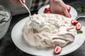 Baker decorating fresh delicious homemade Pavlova cake meringue cake with whipped cream and strawberries. culinary, bakery, food Royalty Free Stock Photo