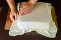 Baker decorating square cake with white fondant