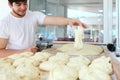 The Baker gives the dough the shape of a tortilla. Portrait of a bakery worker. The man smiles. The process of making tortillas Royalty Free Stock Photo