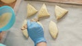 Baker hand inflicts egg mixture with brush on patties before baking on table Royalty Free Stock Photo