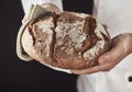 Baker hands holding fresh loaf of rye bread