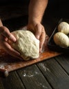 The baker hands knead the dough for buns on the kitchen table close-up. The concept of baking pies in the bakery