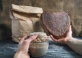 Baker hold in hands glass jar with sourdough and rye bread in shape heart, paper bag whole grain flour on background