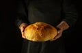 The baker holds round wheat bread in his hands. Serving bread on the table for dinner. The concept of home baking in the bakery Royalty Free Stock Photo