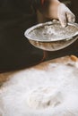 Baker pours flour for making pizza. Chef cooking dough to bake a cake on a wooden table. Royalty Free Stock Photo