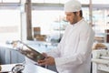 Male chef in uniform holding stainless mixing bowl while inspecting at bakery kitchen, copy space Royalty Free Stock Photo