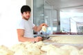 The Baker makes tortillas from the dough. Portrait of a bakery worker. The man smiles. The process of making tortillas Royalty Free Stock Photo