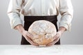 Baker man holding rustic organic loaf of bread in hands