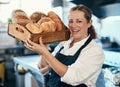 Baker, pastry chef and cafe owner carrying a tray of fresh rolls and bread loaf assortment in a coffee shop. Portrait of Royalty Free Stock Photo