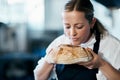 Baker, pastry chef and cafe owner smelling a loaf of fresh baked bread in the kitchen of her coffee shop. Closeup of a Royalty Free Stock Photo