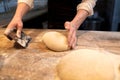 Baker portioning dough with bench cutter at bakery Royalty Free Stock Photo