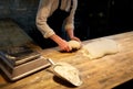 Baker portioning dough with bench cutter at bakery Royalty Free Stock Photo