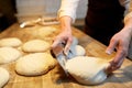 Baker portioning dough with bench cutter at bakery Royalty Free Stock Photo