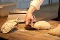 Baker portioning dough with bench cutter at bakery Royalty Free Stock Photo