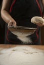 Baker pours flour for making pizza. Chef cooking dough to bake a cake on a wooden table. Royalty Free Stock Photo