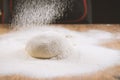 Baker pours flour for making pizza. Chef cooking dough to bake a cake on a wooden table. Royalty Free Stock Photo