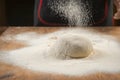 Baker pours flour for making pizza. Chef cooking dough to bake a cake on a wooden table. Royalty Free Stock Photo