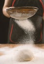 Baker pours flour for making pizza. Chef cooking dough to bake a cake on a wooden table. Royalty Free Stock Photo