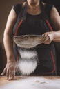 Baker pours flour for making pizza. Chef cooking dough to bake a cake on a wooden table. Royalty Free Stock Photo