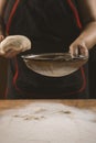 Baker pours flour for making pizza. Chef cooking dough to bake a cake on a wooden table. Royalty Free Stock Photo