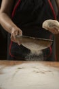 Baker pours flour for making pizza. Chef cooking dough to bake a cake on a wooden table. Royalty Free Stock Photo