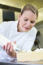 Baker prepares cake in bakehouse with whipped cream Royalty Free Stock Photo