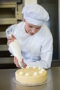 Baker prepares cake in bakehouse with whipped cream Royalty Free Stock Photo