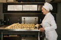 Baker pulling a tray with raw buns with sesame seeds prepared for baking Royalty Free Stock Photo