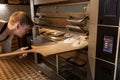 Baker putting dough into bread oven at bakery Royalty Free Stock Photo