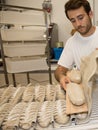 Baker putting unbaked bread dough into hot oven in bakery Royalty Free Stock Photo