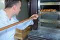 Baker removing bread from oven