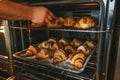 baker removing a tray of croissants from oven