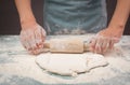 Baker rolls out dough for pizza, flatbread or pastry with rolling pin, prepare ingredients for food, baking for holidays Royalty Free Stock Photo