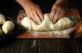 The baker's hands knead the dough before baking the buns. Work environment on the kitchen table in the bakery