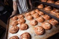 Baker`s hands in mittens hold baking sheet with sweet buns