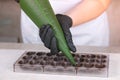 Baker`s hands pouring liquid chocolate filling praline in form from pastry bag. Royalty Free Stock Photo