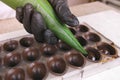Baker`s hands pouring liquid chocolate filling praline in form from pastry bag. Royalty Free Stock Photo