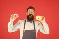 At baker shop. mature man red backdrop. skilled baker with donut dessert. funny hipster cook doughnut. temptation while Royalty Free Stock Photo